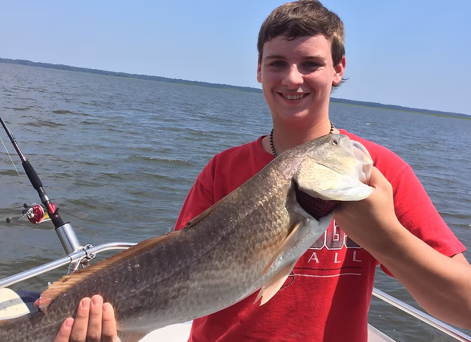 A child holding a redfish caught on a fishing charter