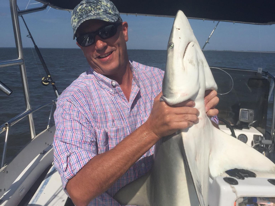 A guest holding a shark from a fishing charter